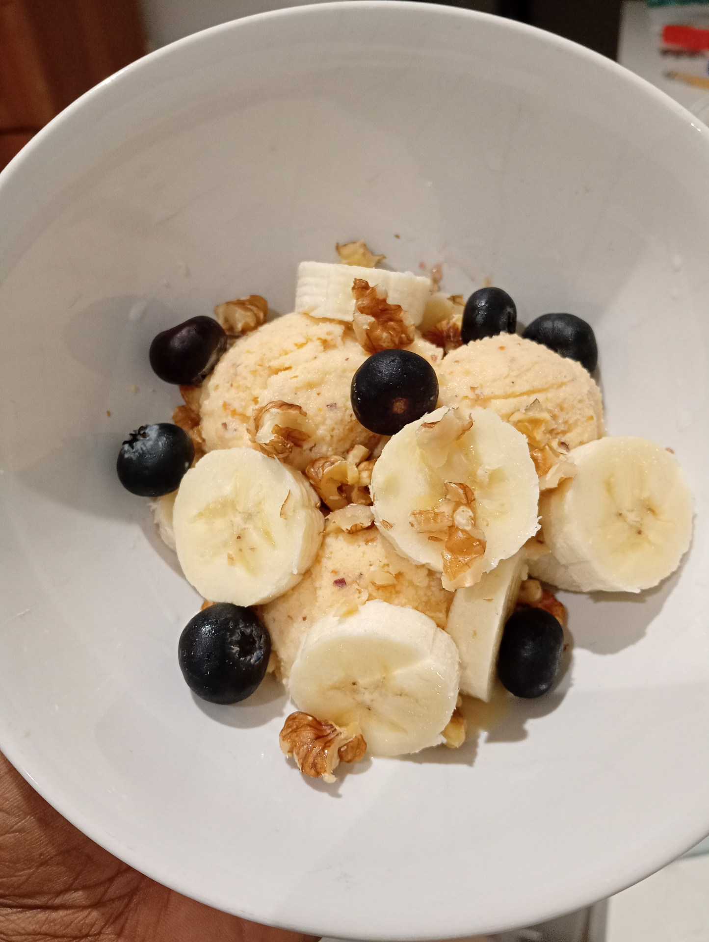 Peach and ricotta ice cream in a bowl with banana, blueberries and walnuts