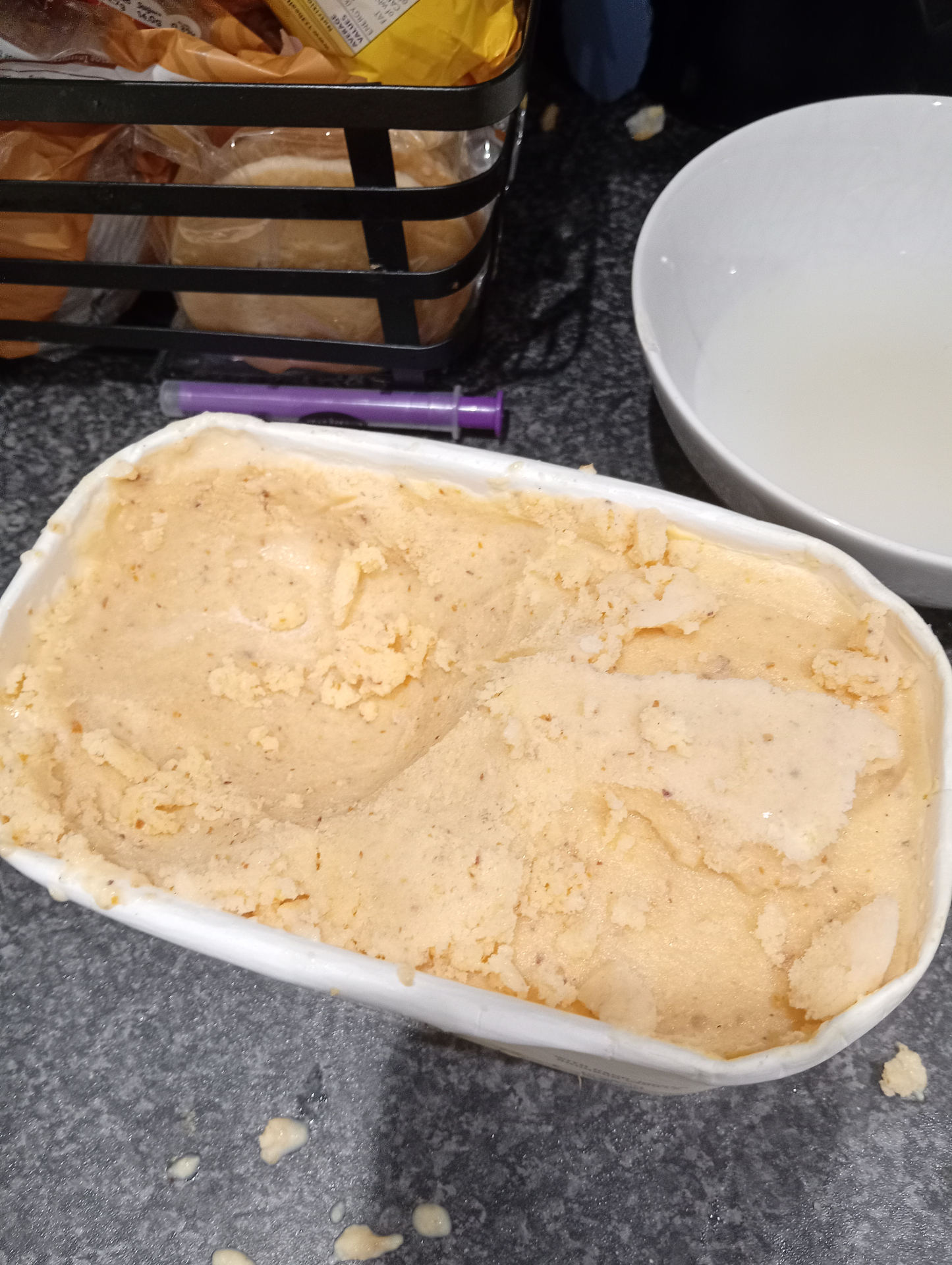 The churned tub of peach and ricotta ice cream on the kitchen counter